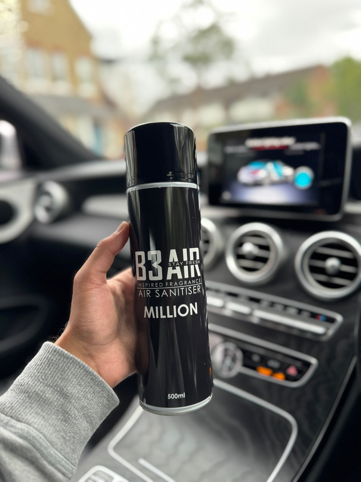 Hand holding B3 AIR Million air freshener spray inside a car